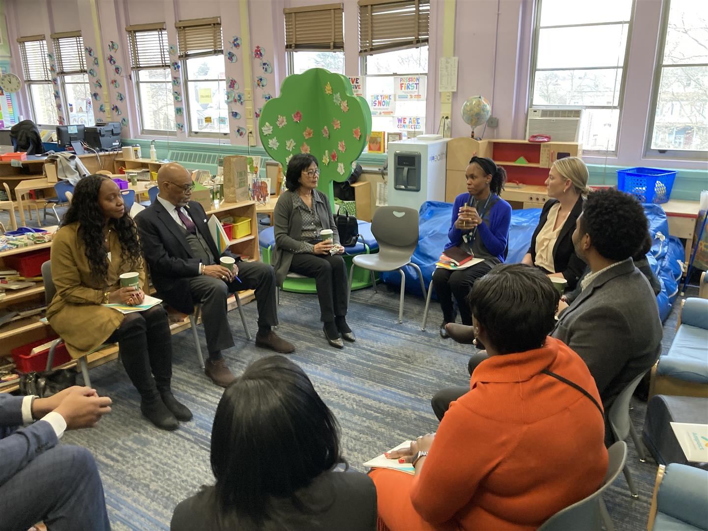 A group of school leaders sit in a circle talking.